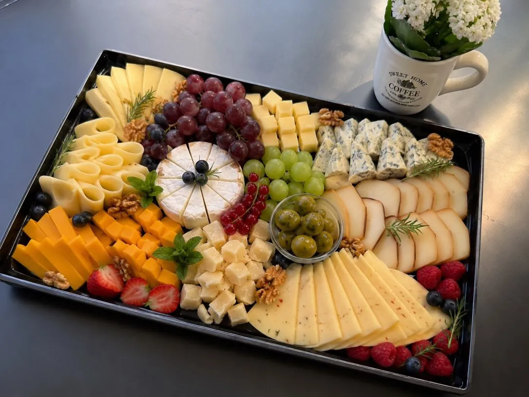 Siera plate: Brie, zilais siers, kūpinātais siers, vīnogas, olīves un ogas uz melnas paplātes