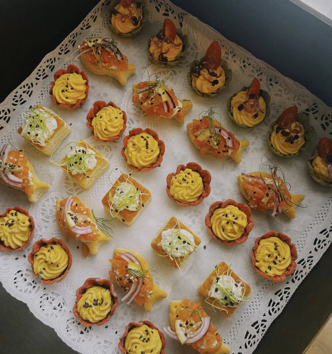 Tartaletes un kārtainās uzkodas ar lasi uz mežģīņu salvetes